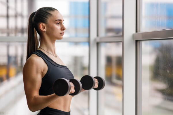 Žena cvičí biceps s jednoručkami