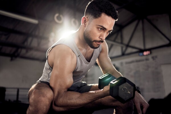 Muž cvičí v posilovně koncentrický zdvih na biceps