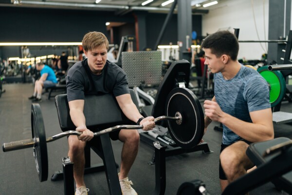 Muž trénuje biceps na Scottově lavici