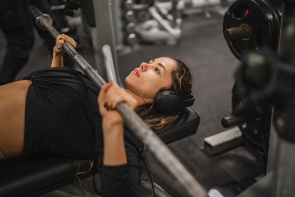 Žena, která provádí bench press (tlak na lavičce s osou)